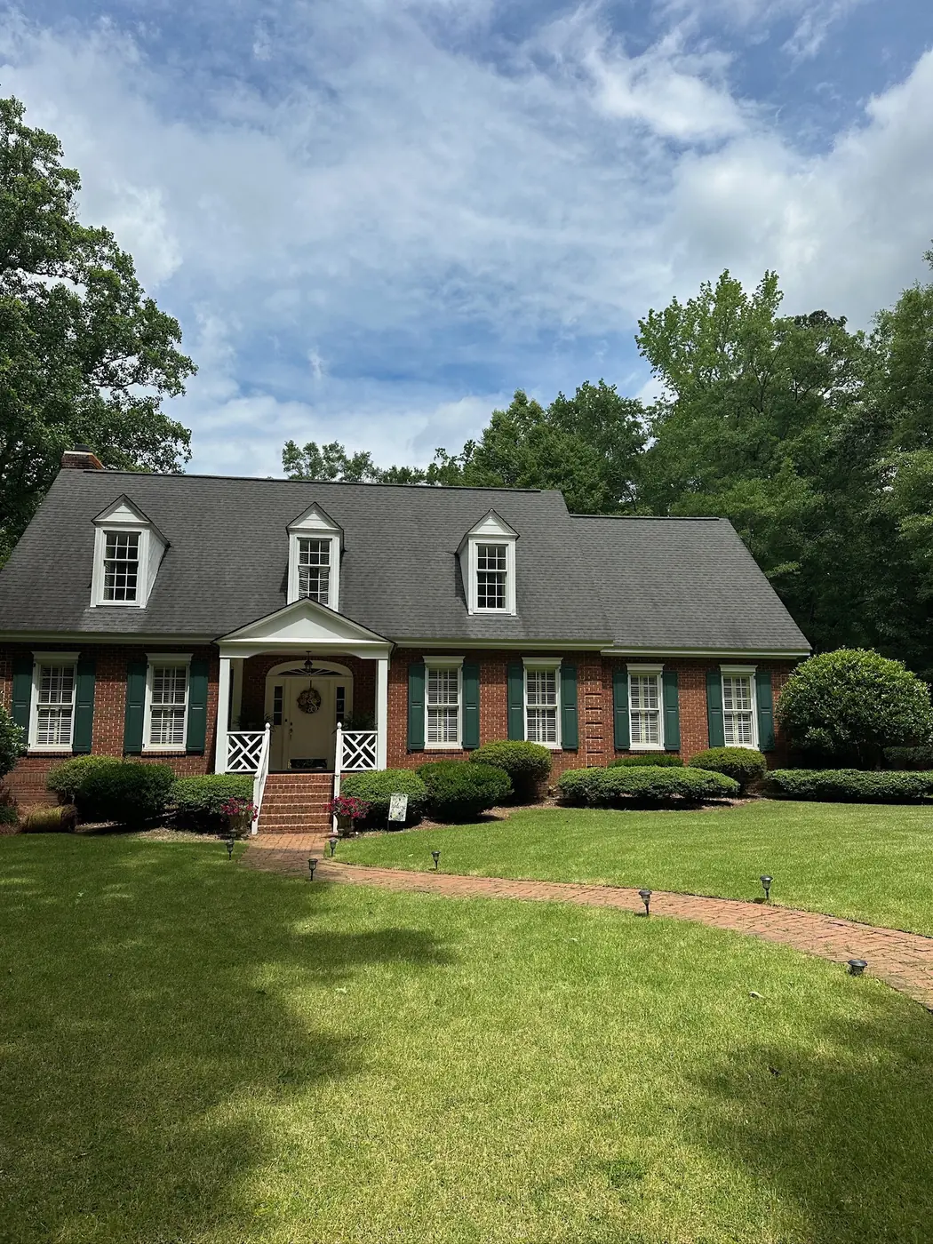 Manicured green lawn and trimmed beds at a brick colonial home
