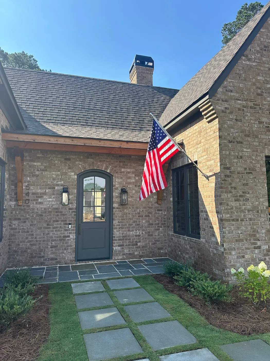 Manicured entrance with a flagstone path at a brick home