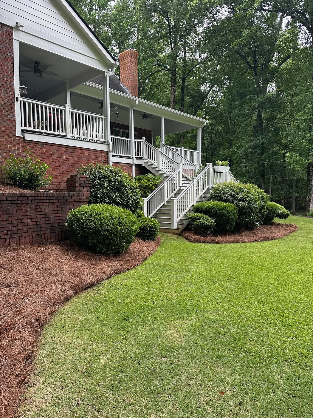 Trimmed beds and green lawn at a farmhouse with a front porch