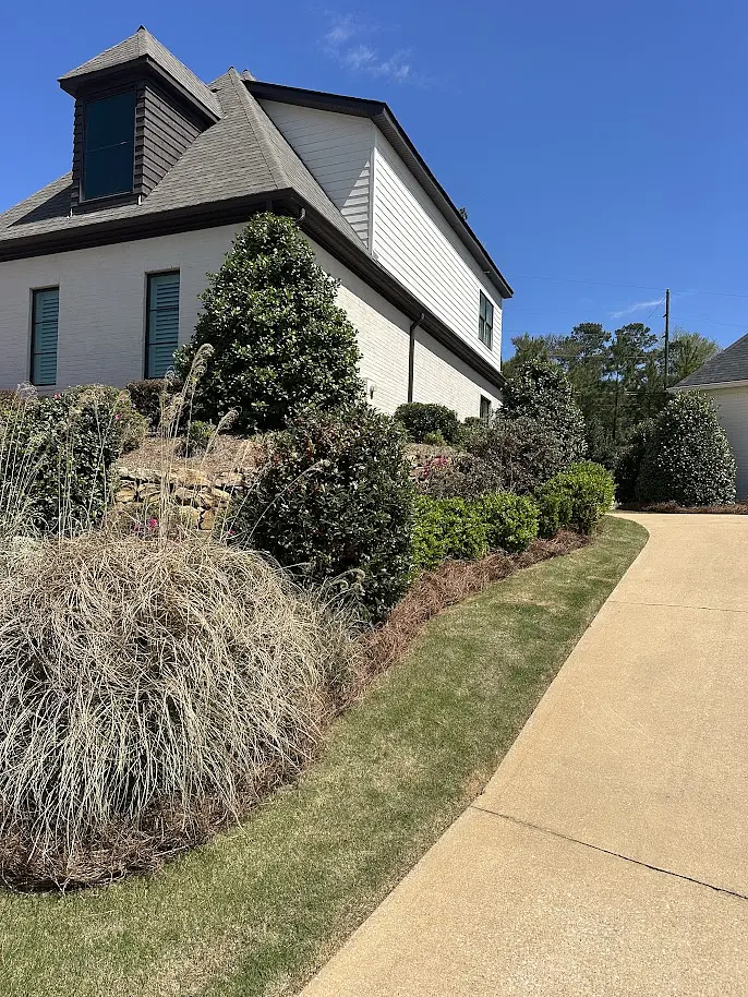 Maintained side-yard beds along a white brick home