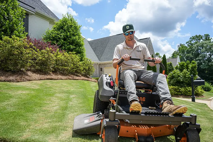 Rolling Lawns crew mowing a freshly striped lawn in Auburn, Alabama
