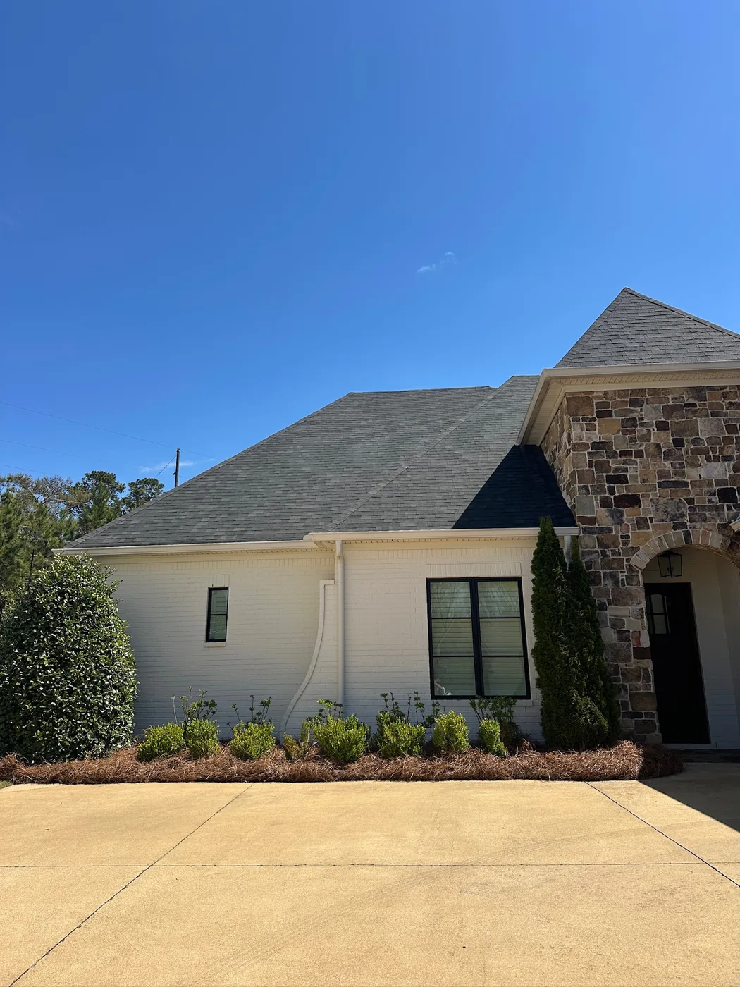 Fresh pine straw beds lining the drive at a stone and stucco home