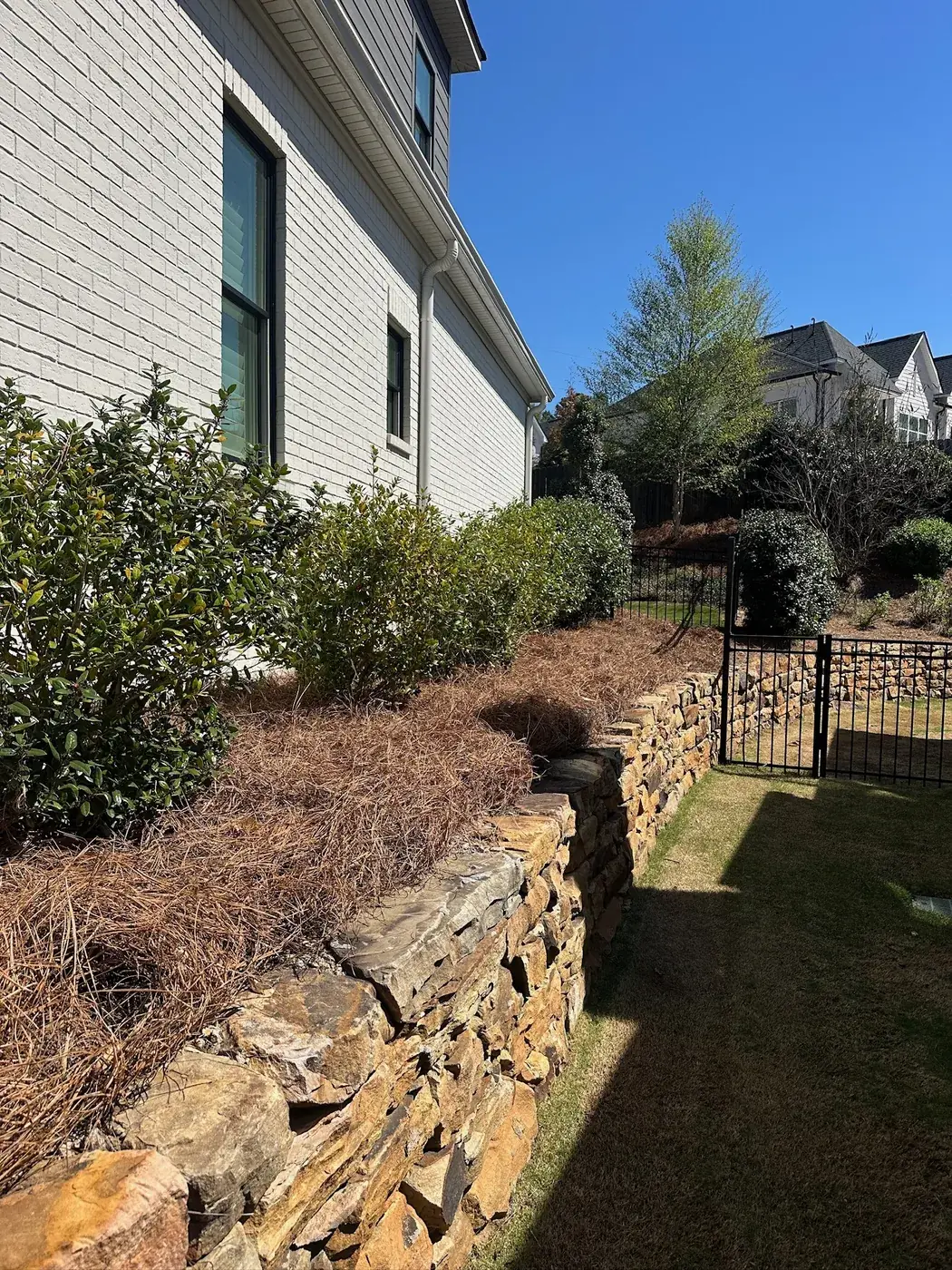 Fresh pine straw beds above a stacked stone retaining wall