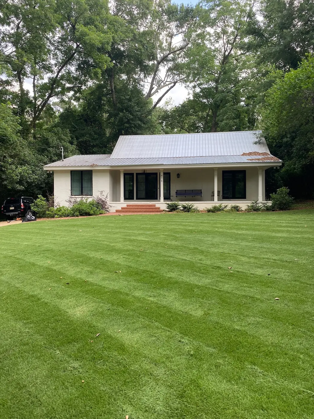 Bold mowing stripes across a full front lawn leading to a white ranch home